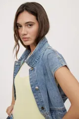 Chaleco de jean negro de calce relajado, con cuello camisero, cierre frontal con botones metálicos y bolsillos delanteros con solapa.