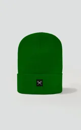 Gorro de tejido de punto color verde, de estilo beanie con borde doblado y un pequeño parche negro con un logo blanco de tijeras cruzadas.