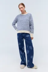 Sweater color crudo con jacquard floreado en lurex negro y puños con textura delicada.