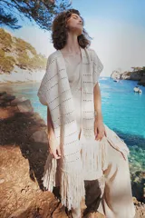 Chaleco largo de tejido de punto color azul verdoso, sin mangas y con flecos en el ruedo. Presenta calados con diseño geométrico.