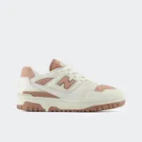Championes urbanos New Balance modelo 550, color blanco y beige con detalles en rosa, confeccionados en cuero y gamuza, con logo "N" característico en los laterales y suela de goma.