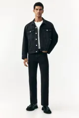 Campera trucker de denim de algodón rígido, color negro lavado, con cuello, botones de metal y canesú delantero y trasero. Posee bolsillos superiores con solapa y botón, bolsillos laterales insertados, puños abotonados y trabilla ajustable con botones en los laterales del bajo.