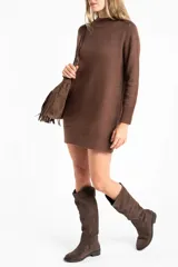 Vestido corto de punto color marrón, con cuello alto, mangas largas con puños acanalados y ruedo acanalado. Presenta un diseño de corte recto y holgado.