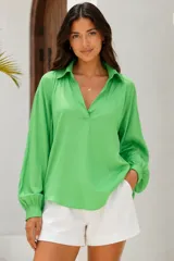 Blusa verde de viscosa con cuello en V y cuello camisero, manga larga abullonada con puños elásticos y dobladillo redondeado.