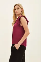 Camisa negra de poliéster con corte recto, cuello mao y volados en las mangas.