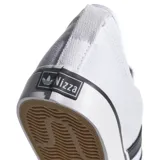 Championes Adidas modelo Nizza, de lona blanca con las tres tiras laterales en negro y suela de goma vulcanizada con detalle de línea negra.