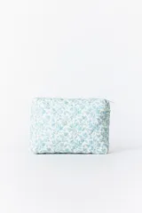 Necessaire mediano de tela acolchada con diseño matelassé y estampado floral en color celeste sobre fondo blanco. Cuenta con cierre superior de cremallera.