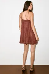 Vestido mini marrón terracota con finas rayas verticales de hilo metalizado, escote en V, tirantes finos ajustables, cierre frontal con botones y detalle de volados desflecados en el borde inferior.