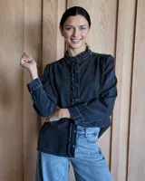 Camisa de jean azul con cuello alto con volados y volados en el frente.