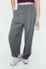 Pantalón de tiro alto con diseño de rayas verticales, corte recto y holgado. Presenta pliegues frontales, bolsillos laterales y bajo ajustable con botón.