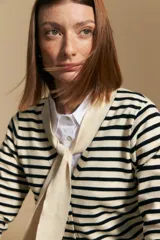 Cárdigan de tejido de punto a rayas horizontales anchas, color crema y negro. Presenta un cuello tipo chal que se anuda al frente como un lazo.