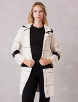 Chaqueta de tejido suave con estampado a cuadros en blanco, negro y beige. Presenta cuello con solapa, cierre frontal con un botón y bolsillos delanteros.