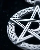 Collar de acero con dije circular que presenta un diseño de estrella pentagrama con detalles de nudos celtas en el borde. Incluye cadena de eslabones finos.
