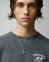 Collar de cadena fina con dije colgante en forma de bota vaquera con detalles grabados, acabado en color plata envejecida.