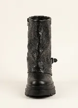 Bota corta de cuero negro con diseño de polaina superpuesta, detalle de tachas metálicas en el lateral y correa con hebilla ajustable. Cuenta con suela track de goma y taco cuadrado.