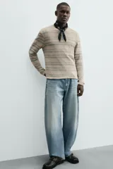 Camiseta de manga larga con cuello redondo y ajuste relajado, confeccionada en tejido de punto con estructura abierta y patrón de rayas horizontales.