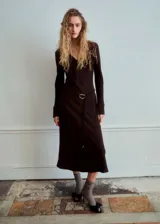 Vestido midi marrón oscuro de corte recto y escote en V, con mangas largas y un cinturón fino con hebilla metálica dorada en la cintura.