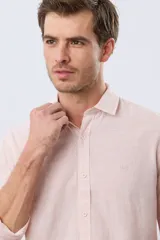Camisa de lino a rayas finas en tonos beige y blanco, de manga larga con puños vueltos, cuello camisero y cierre frontal de botones. Cuenta con un pequeño logo bordado en el pecho.
