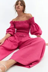 Crop top blanco con escote off-shoulder, punto panal en el torso y volados en el escote.