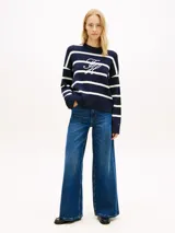 Sweater amplio de punto Tommy Hilfiger confeccionado en puro algodón peinado, de diseño a rayas horizontales azul marino y blancas, con cuello redondo y hombros caídos. Presenta el logo bordado en fuente Script en la parte delantera.