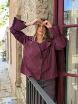 Chaqueta de corte recto y diseño cruzado con botones frontales. Presenta cuello solapa y mangas largas con puños fruncidos, confeccionada en tejido de algodón.