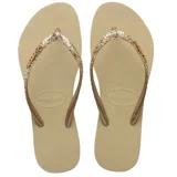 Sandalias tipo ojota Havaianas modelo Slim Glitter II, color beige arena. Presentan tiras finas con acabado de glitter brillante y logo de la marca en relieve.