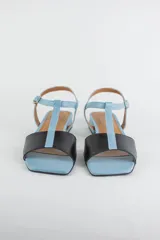Sandalias de cuero combinadas en negro y marfil, con diseño de tiras en T, taco cuadrado bajo y pulsera con hebilla ajustable al tobillo.