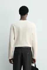 Camiseta relaxed fit de manga larga confeccionada en tejido waffle con mezcla de algodón y cáñamo. Presenta cuello redondo con cierre frontal parcial de botones.