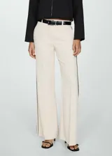 Pantalon de corte wideleg en color beige, confeccionado en tejido fluido. Presenta diseño de rayas laterales en contraste, trabillas para cinturón, dos bolsillos laterales y cierre oculto de botón, gancho y cremallera.