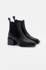 Bota corta tipo chelsea de cuero, con taco cuadrado y punta cuadrada. Presenta paneles laterales elásticos y una suela con plataforma sutil.
