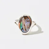 Anillo plateado con una piedra ovalada de nácar iridiscente.