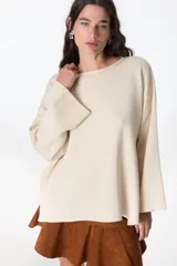 Sweater de tejido de punto color crudo, con cuello redondo, corte holgado y mangas largas con terminación acampanada.