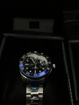 Reloj Rolex Submariner "Batman" con bisel giratorio unidireccional negro y azul, esfera negra con índices luminiscentes, lupa sobre la ventana de fecha y malla de acero inoxidable.