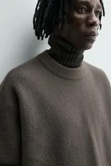 Jersey de punto con textura efecto pelo, corte relajado, cuello redondo y manga larga con acabados en rib.