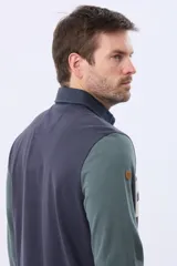 Remera tipo polo de manga larga con diseño color block en azul marino, verde y una franja central en beige con el texto Legacy Original Brand estampado. Presenta cuello camisero con cierre de botones y puños acanalados.