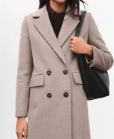 Abrigo de paño color beige, con diseño cruzado de doble botonadura, solapas clásicas y bolsillos laterales con solapa. Presenta un corte estructurado y elegante.