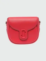 Cartera Marc Jacobs modelo The Covered J Marc Saddle Bag, color rojo, con solapa frontal y cierre magnético con el logo "J Marc" cubierto. Incluye correa de hombro ajustable y herrajes dorados.