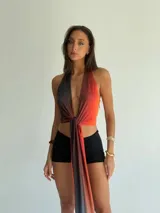 Top halter de tela brillante con efecto degradado que va del negro al naranja rojizo, anudado al frente.