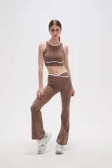 Top deportivo sin mangas, color camel, con cuello redondo y detalles de ribete en color blanco. Presenta un diseño al cuerpo con costuras decorativas en el bajo.