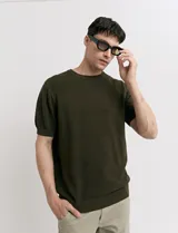 Remera de punto color beige, de manga corta y cuello redondo.