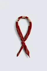 Bandana cuadrada confeccionada en tejido fluido de lyocell, color bordó con estampado en contraste beige. Presenta un diseño central de cuadros rodeado de motivos abstractos y caligrafía.