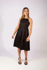 Vestido midi color negro con escote cuadrado, tirantes finos y falda con vuelo. Presenta detalle de botones decorativos en el lateral de la cintura.