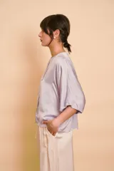 Blusa de satén color lila con escote en V y cierre frontal con botones.