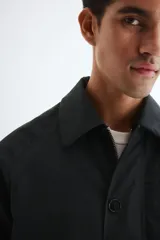 Campera de sarga levemente acolchada con cuello inglés, cierre frontal y solapa con botones. Presenta mangas raglán, bolsillos insertados delanteros, un bolsillo interior y cordón ajustable en el bajo.