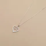 Conjunto de collar y dije de corazón calado en plata 925 con circonias. El dije tiene la palabra "MAMA" y un moño.