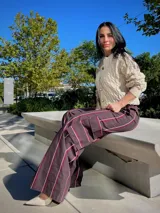 Pantalon de corte cargo con diseño a rayas verticales en tonos marrón, blanco y bordó. Presenta bolsillos laterales tipo cargo, tiro alto y pernera ancha.