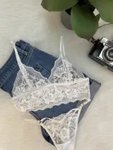Conjunto de lencería compuesto por un top bralette de encaje floral con breteles regulables y una tanga colaless a juego con tiras laterales ajustables.
