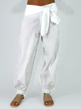 Pantalón beige con textura arrugada, de corte holgado estilo balloon con puños elásticos en los tobillos y cintura alta con faja y lazo ajustable.