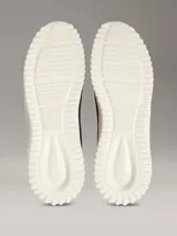 Zapatillas tipo runner Calvin Klein en color negro con suela de EVA blanca y detalles en verde claro en el talón. Presentan diseño tipo calcetín, parte superior de malla técnica y logo de la marca en la lengüeta y el lateral.