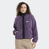 Campera de polar tipo corderito en color violeta, con cuello alto, cierre frontal con botones a presión y detalles en negro. Cuenta con un bolsillo frontal con cierre y logo de la marca.